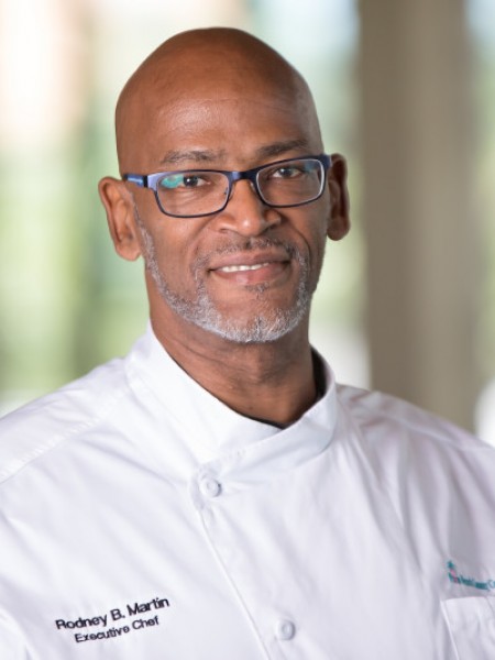 Photo Head shot of our Executive Chef Rodney Martin in a white chef's coat