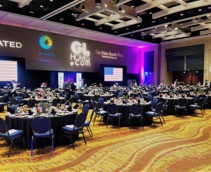 Banquet room set up in all black linens and chair covers with masquerade décor on the tables