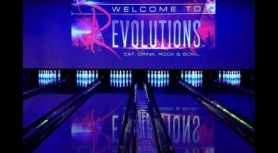 Photo of four bowling lanes with glow and the dark pins and purple lighting.